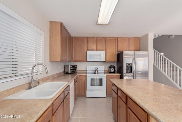 kitchen with light tile patterned floors, white appliances, and sink