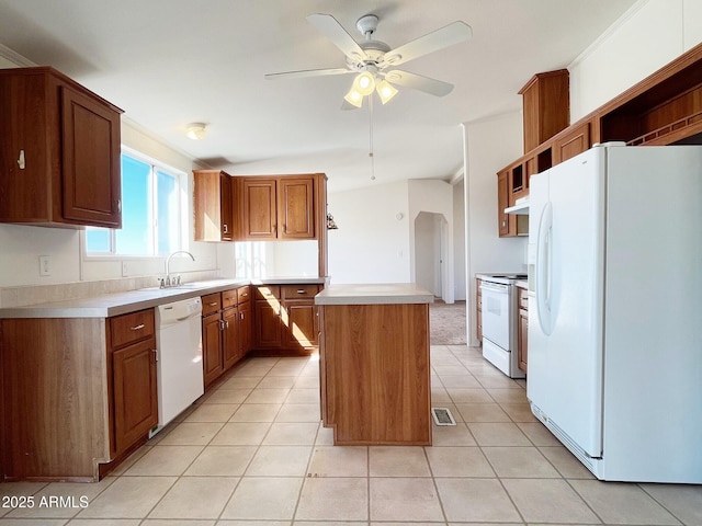 kitchen featuring white appliances, light tile patterned floors, arched walkways, light countertops, and a sink