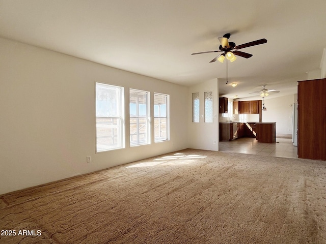 unfurnished living room featuring light carpet and a ceiling fan