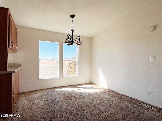 unfurnished dining area featuring carpet, visible vents, and a chandelier