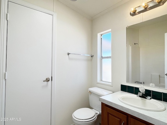 bathroom with a shower, crown molding, vanity, and toilet