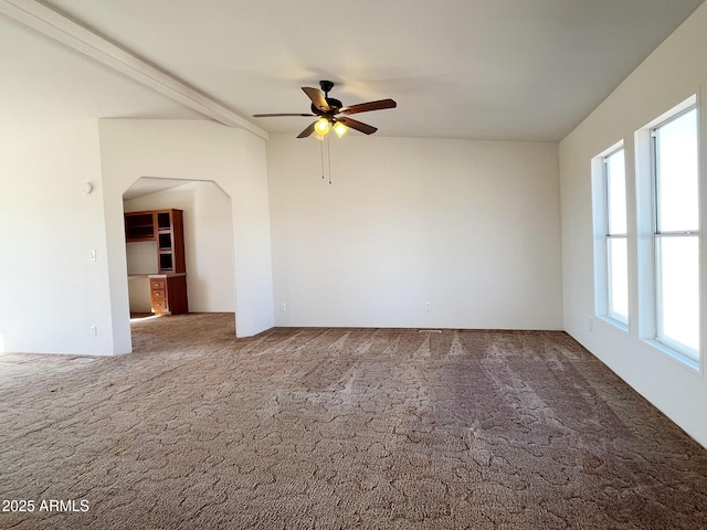 spare room featuring a healthy amount of sunlight, carpet, arched walkways, and ceiling fan