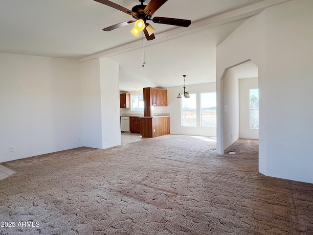 empty room featuring arched walkways, light carpet, vaulted ceiling, and ceiling fan