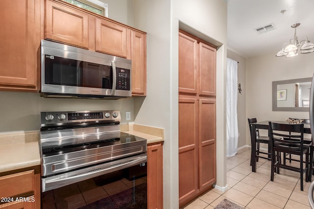 kitchen with light tile patterned flooring, stainless steel appliances, hanging light fixtures, and a chandelier