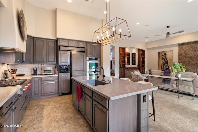 kitchen featuring ceiling fan with notable chandelier, sink, hanging light fixtures, an island with sink, and stainless steel appliances