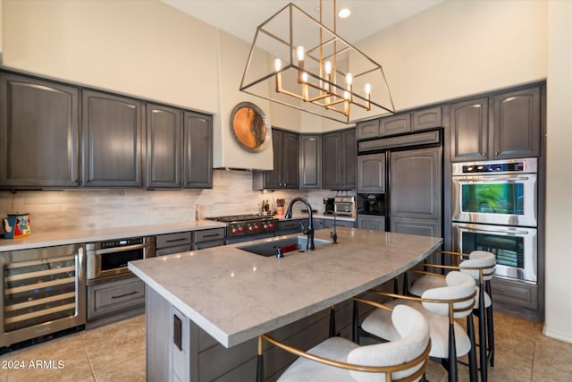 kitchen featuring stainless steel appliances, a center island with sink, beverage cooler, and sink