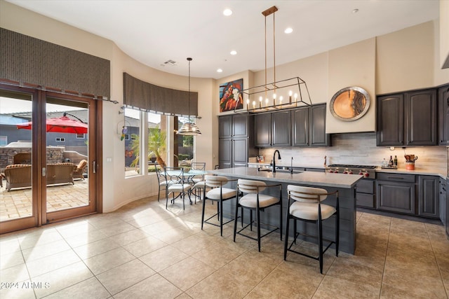 kitchen with dark brown cabinetry, sink, an island with sink, and light tile patterned flooring