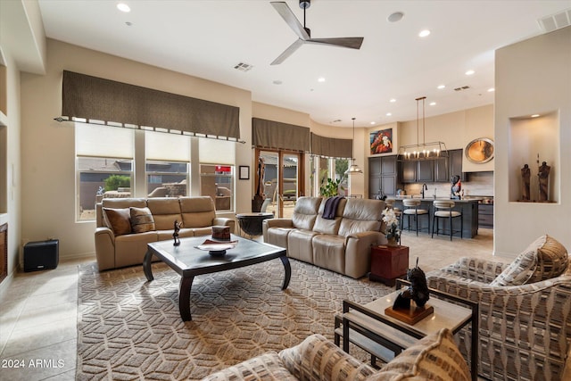 tiled living room with a high ceiling, ceiling fan with notable chandelier, and a wealth of natural light