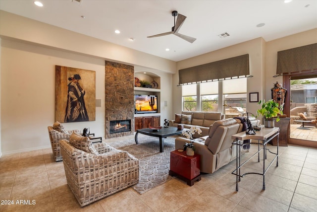 living room featuring built in shelves, a healthy amount of sunlight, a stone fireplace, and ceiling fan