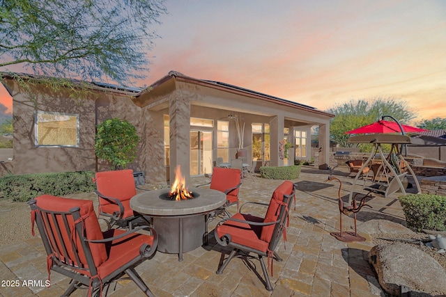 patio terrace at dusk with ceiling fan and an outdoor fire pit