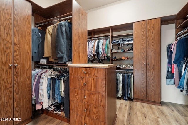 walk in closet with light hardwood / wood-style floors