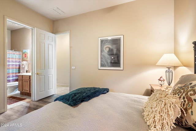 bedroom with light hardwood / wood-style floors and connected bathroom