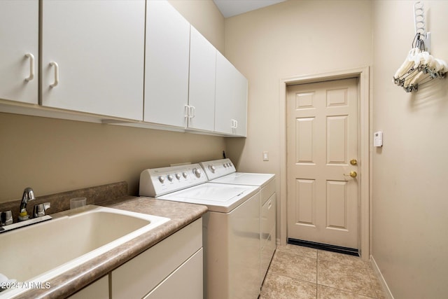 clothes washing area featuring light tile patterned flooring, cabinets, separate washer and dryer, and sink