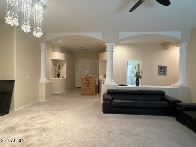 carpeted living room with decorative columns and ceiling fan