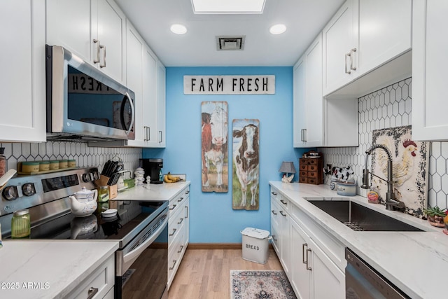 kitchen featuring visible vents, appliances with stainless steel finishes, tasteful backsplash, and a sink