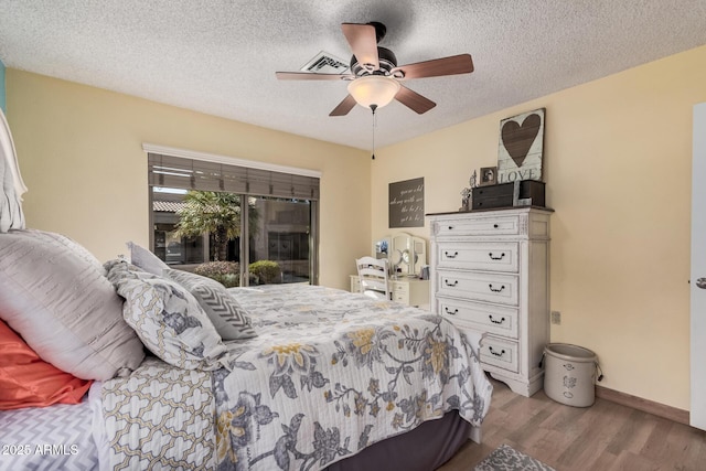 bedroom featuring baseboards, ceiling fan, wood finished floors, access to exterior, and a textured ceiling