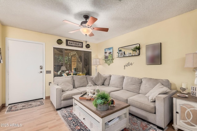 living area with a ceiling fan, a textured ceiling, and light wood finished floors