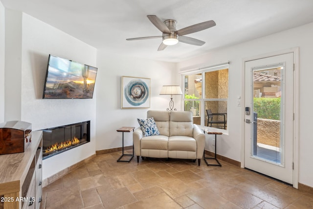 8787 E Mountain View Rd Unit 1100, Scottsdale, AZ 85258 - living area with stone tile floors, baseboards, a glass covered fireplace, and a ceiling fan