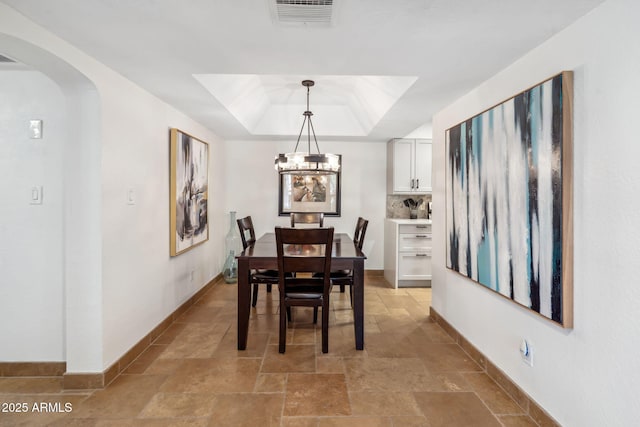 8787 E Mountain View Rd Unit 1100, Scottsdale, AZ 85258 - dining area with stone tile floors, a raised ceiling, arched walkways, and a chandelier