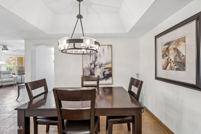 8787 E Mountain View Rd Unit 1100, Scottsdale, AZ 85258 - dining area featuring a chandelier, stone tile floors, a raised ceiling, a ceiling fan, and arched walkways