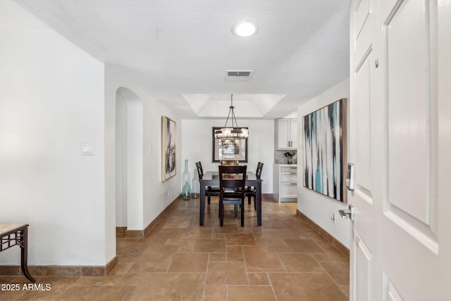 8787 E Mountain View Rd Unit 1100, Scottsdale, AZ 85258 - dining room featuring baseboards, light stone finish floors, a raised ceiling, and arched walkways
