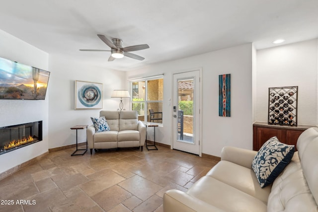 8787 E Mountain View Rd Unit 1100, Scottsdale, AZ 85258 - living room featuring ceiling fan, stone tile flooring, baseboards, a glass covered fireplace, and recessed lighting