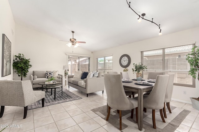 dining space featuring light tile patterned floors, a ceiling fan, rail lighting, and vaulted ceiling