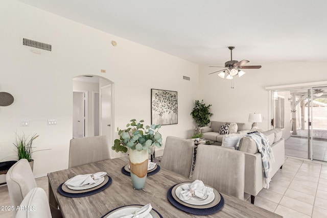 dining space with arched walkways, ceiling fan, and light tile patterned flooring