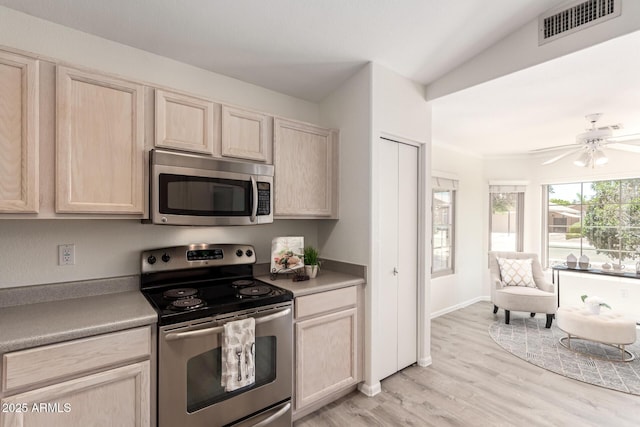 kitchen featuring appliances with stainless steel finishes, light brown cabinetry, light wood-type flooring, a ceiling fan, and light countertops