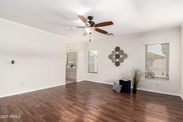 unfurnished room featuring healthy amount of natural light, a ceiling fan, arched walkways, wood finished floors, and ornamental molding