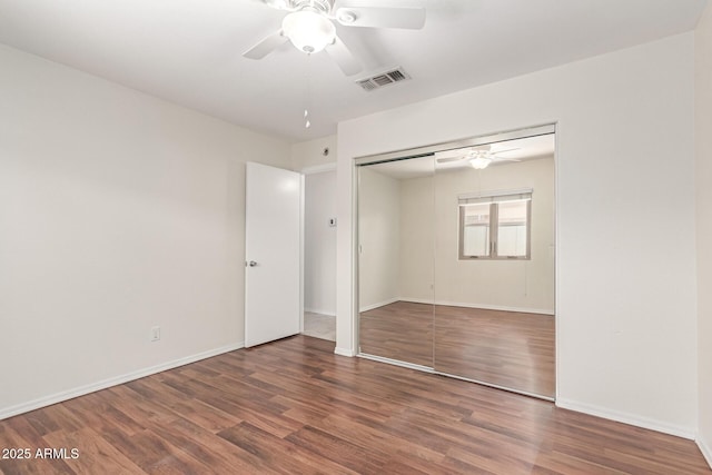 unfurnished bedroom featuring wood finished floors, baseboards, a closet, and a ceiling fan