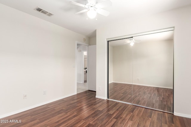 unfurnished bedroom featuring wood finished floors, a closet, baseboards, and a ceiling fan