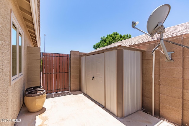 view of patio / terrace featuring a gate, an outbuilding, and a shed