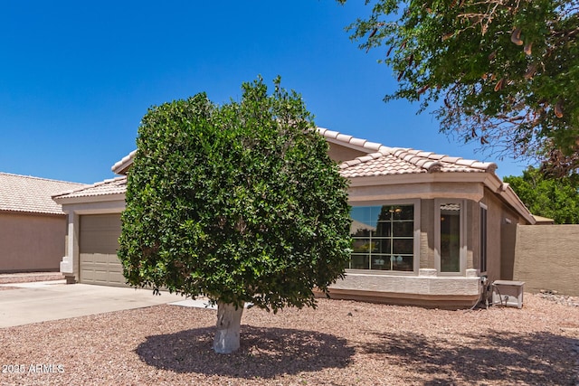view of front of home featuring a tile roof, a garage, stucco siding, and driveway