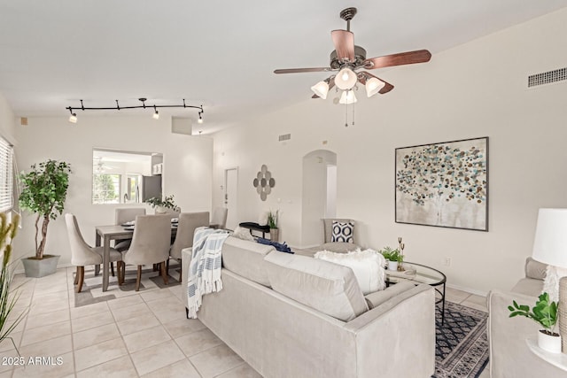 living room featuring light tile patterned flooring, arched walkways, track lighting, and ceiling fan