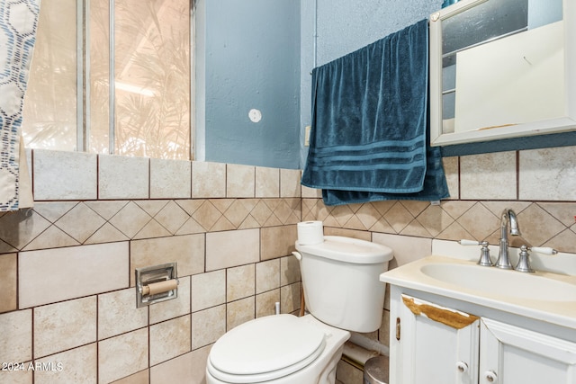 bathroom with tile walls, vanity, toilet, and tasteful backsplash