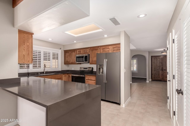 14602 N 63rd Pl, Scottsdale, AZ 85254 - kitchen featuring stainless steel appliances, a sink, dark countertops, a peninsula, and arched walkways