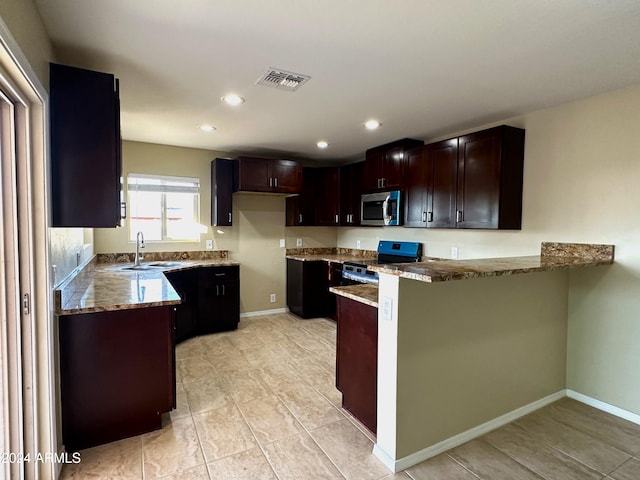 kitchen featuring black range oven, kitchen peninsula, sink, dark brown cabinetry, and light stone counters