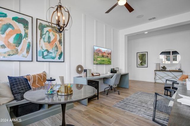 living room with ceiling fan with notable chandelier and light hardwood / wood-style floors