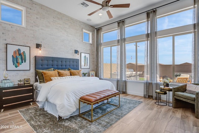 bedroom with light hardwood / wood-style flooring, a high ceiling, and ceiling fan