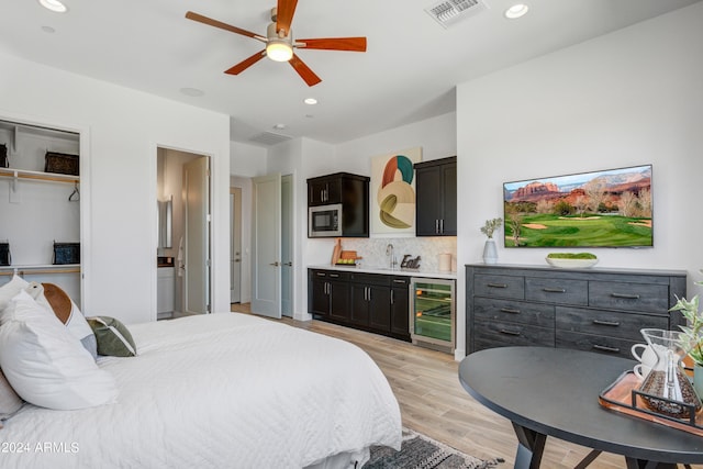 bedroom featuring light hardwood / wood-style flooring, ceiling fan, wine cooler, and a closet