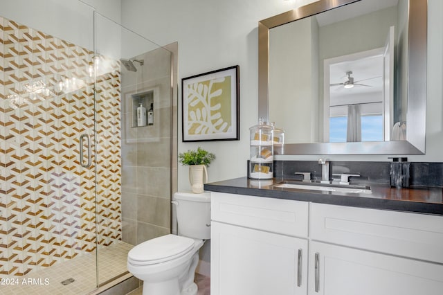 bathroom featuring vanity, toilet, ceiling fan, and a shower with door