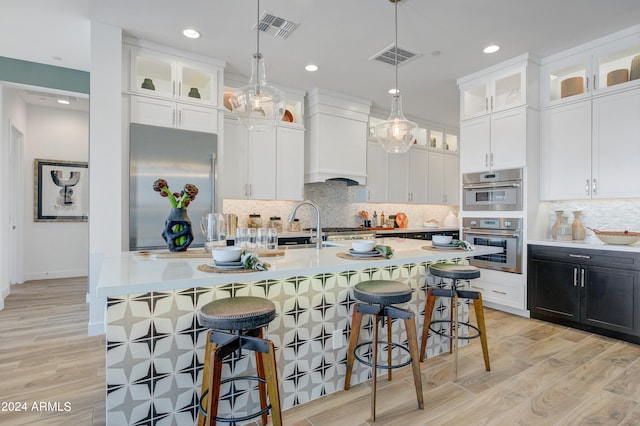 kitchen featuring pendant lighting, stainless steel appliances, light hardwood / wood-style flooring, and white cabinetry