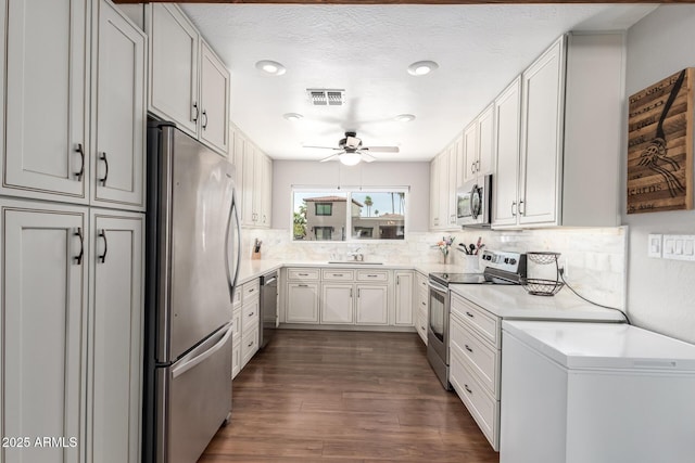 7736 E Rancho Vista Dr, Scottsdale, AZ 85251 - kitchen featuring stainless steel appliances, a ceiling fan, tasteful backsplash, dark wood-style floors, and light countertops
