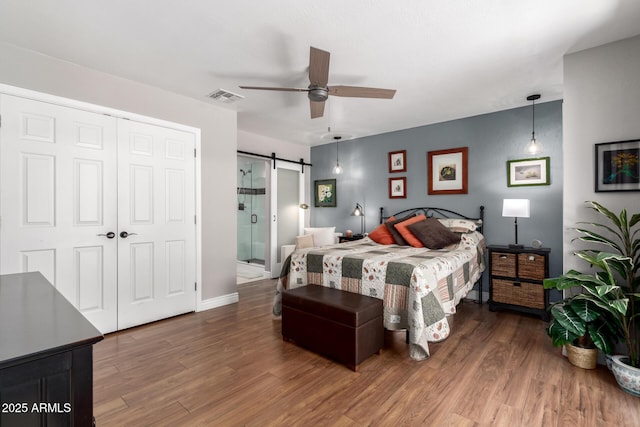 7736 E Rancho Vista Dr, Scottsdale, AZ 85251 - bedroom with a barn door, wood finished floors, a closet, a ceiling fan, and baseboards