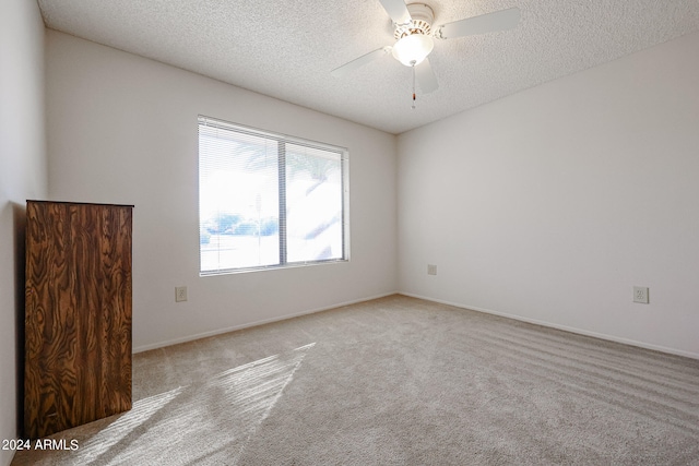 carpeted empty room with ceiling fan and a textured ceiling