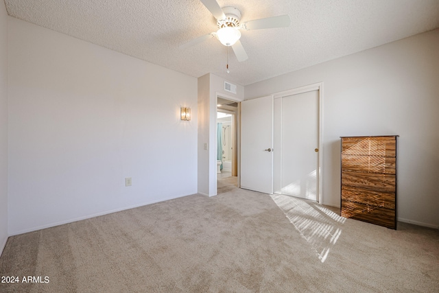 unfurnished bedroom with ceiling fan, light colored carpet, a textured ceiling, and a closet