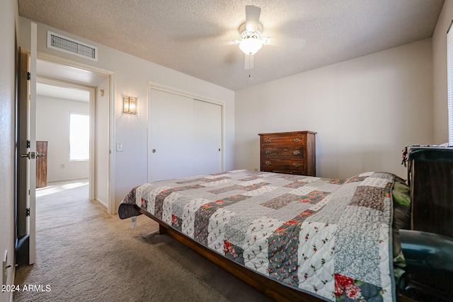 carpeted bedroom featuring a closet, a textured ceiling, and ceiling fan