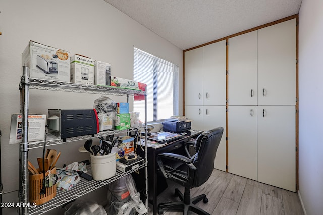 office area with light hardwood / wood-style floors and a textured ceiling