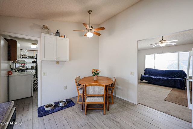 dining space featuring a textured ceiling, light hardwood / wood-style flooring, lofted ceiling, and washer / dryer